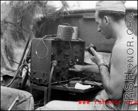 A GI operates a portable radio from the back of a vehicle in the CBI during WWII.