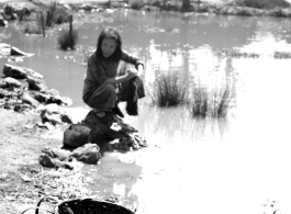 Local people in Yunnan province, China: A woman washes cloth in a village pond. During WWII.  From the collection of Eugene T. Wozniak.