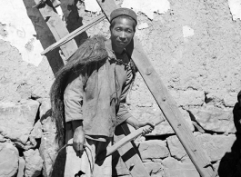 A farmer in a village near Yangkai shoulders a rake used to gather roots and stalks from ground that has been plowed. During WWII.