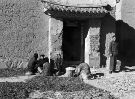 Local people in Yunnan province, China, chatting, sorting pea pods, or waiting as greens dry in the sun. During WWII.
