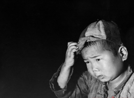 Local people in China during WWII: A Chinese child wearing a cap.