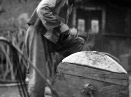 A craftsman repairing a wooden wheel in WWII China. 