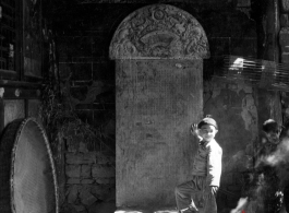 During WWII a boy stands in front of a stone tablet in the entry area of a temple or other building, probably in Yunnan province.