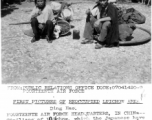 Two local civilians sit on the ground in destroyed Liuzhou after the return of Chinese and American forces on the tails of the Japanese retreat. In WWII.