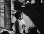 A child holds a bamboo water pipe in China during WWII.