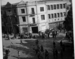 Scenes around Kunming city, Yunnan province, China, during WWII: Corner with curbside sellers and cloth market.
