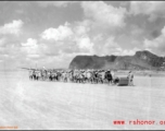 Laborers pull roller at Liuzhou during WWI, in 1945. A C-54 transport plane can be seen in the distance.